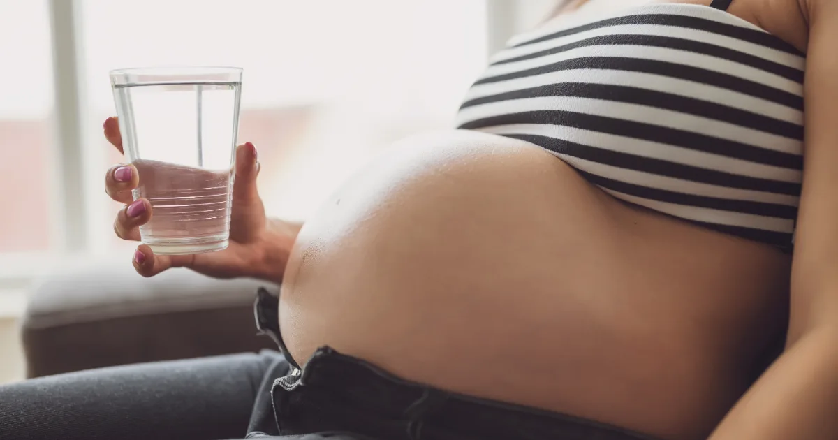 pregnant-woman-drinking-water.jpg Close-up of a pregnant woman holding a clear glass of drinking water.